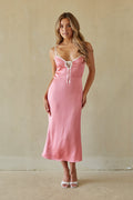 Woman wearing a pink slip dress against a plain background