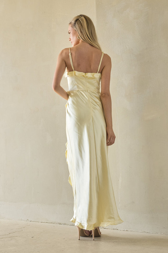Woman wearing a light yellow dress against a plain background