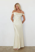 Woman wearing a long off-shoulder yellow dress against a white background