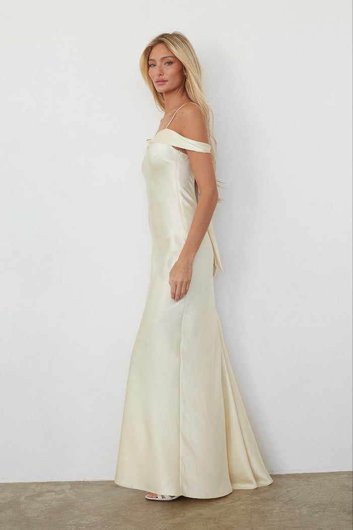 Woman wearing a long, off-shoulder yellow dress against a white background