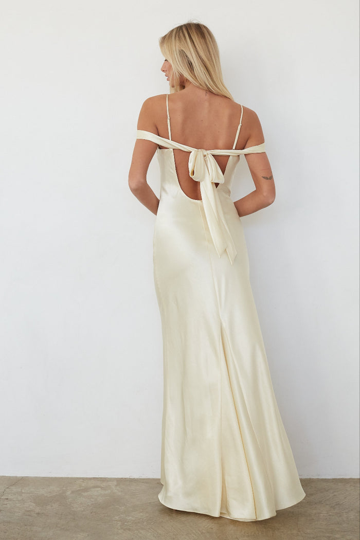 Woman wearing a long, off-shoulder yellow dress with a white background