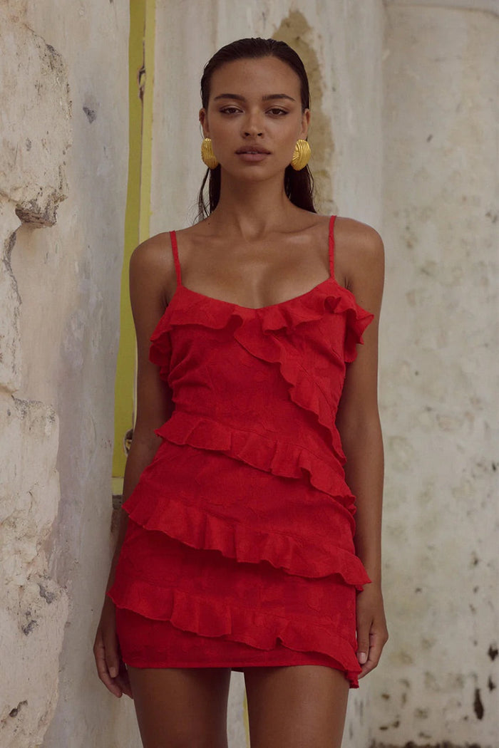 red-image | Woman wearing a red ruffled dress against a textured wall.