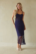 blue-image | Woman wearing a navy blue dress with sheer lace details against a beige background