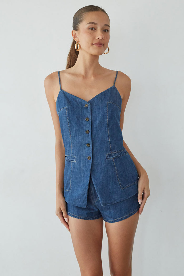 Woman wearing a blue denim romper against a plain background