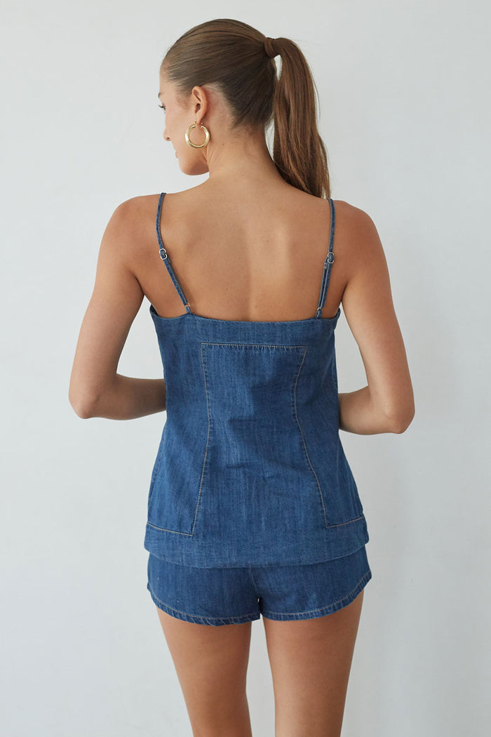 Woman wearing a denim romper against a plain background