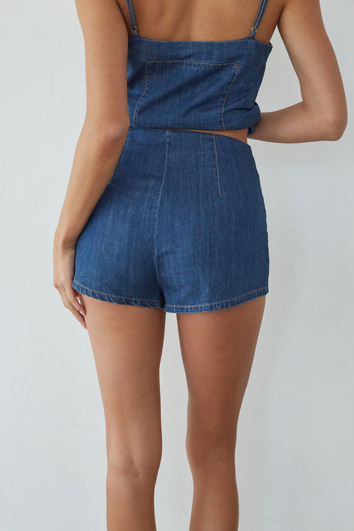 Denim romper worn by a person on a plain background