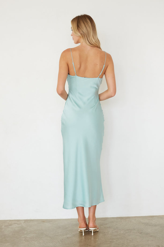 Woman wearing a light blue dress with thin straps against a white background