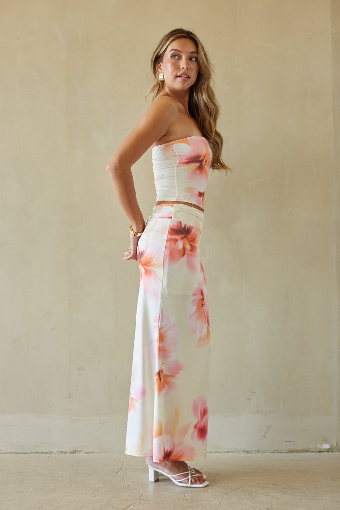 Woman wearing a strapless floral dress against a plain background