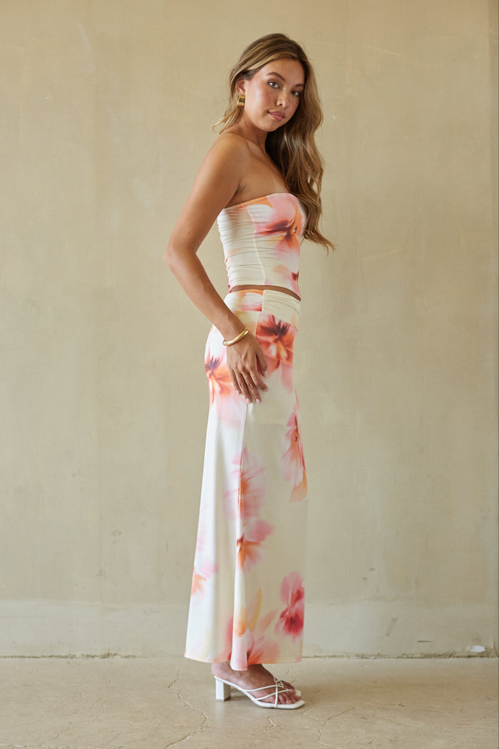 Woman wearing a strapless floral dress against a plain background