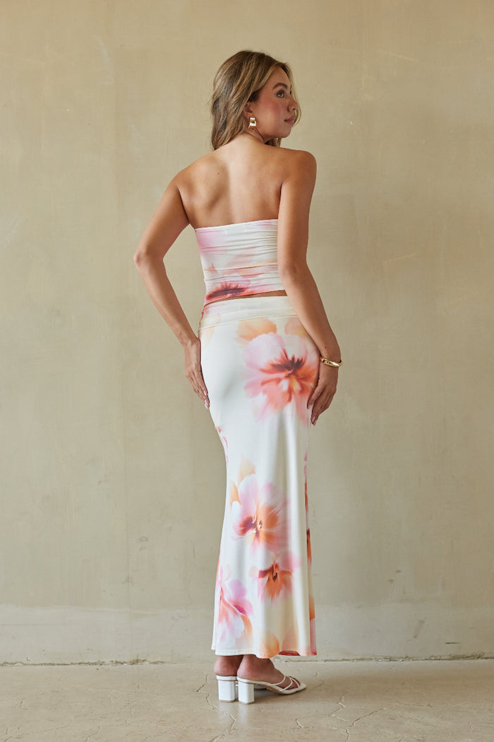 Woman wearing a floral strapless dress against a plain background
