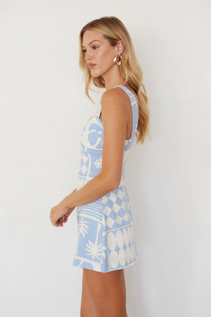 Woman wearing a blue and white patterned dress against a white background
