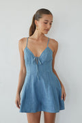 Woman wearing a blue denim dress against a white background