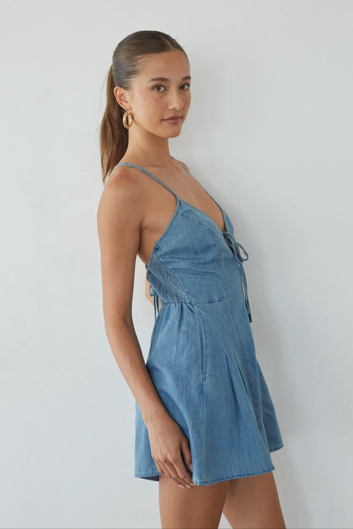 Woman wearing a blue denim dress against a white background