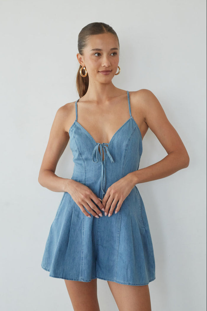 Woman wearing a blue denim dress against a plain background