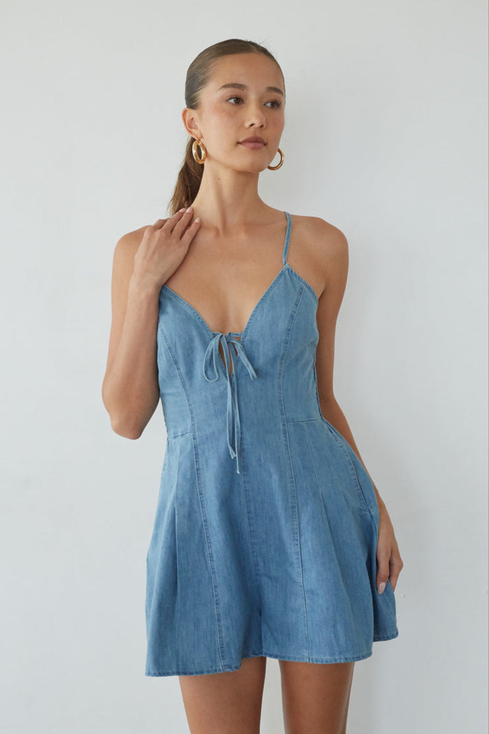 Woman wearing a blue denim dress against a white background