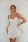 white-image | A woman wearing a white floral embroidered mini dress with adjustable spaghetti straps and a flowy paneled skirt.