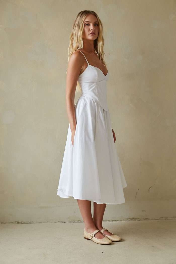 Woman wearing a white dress against a beige background