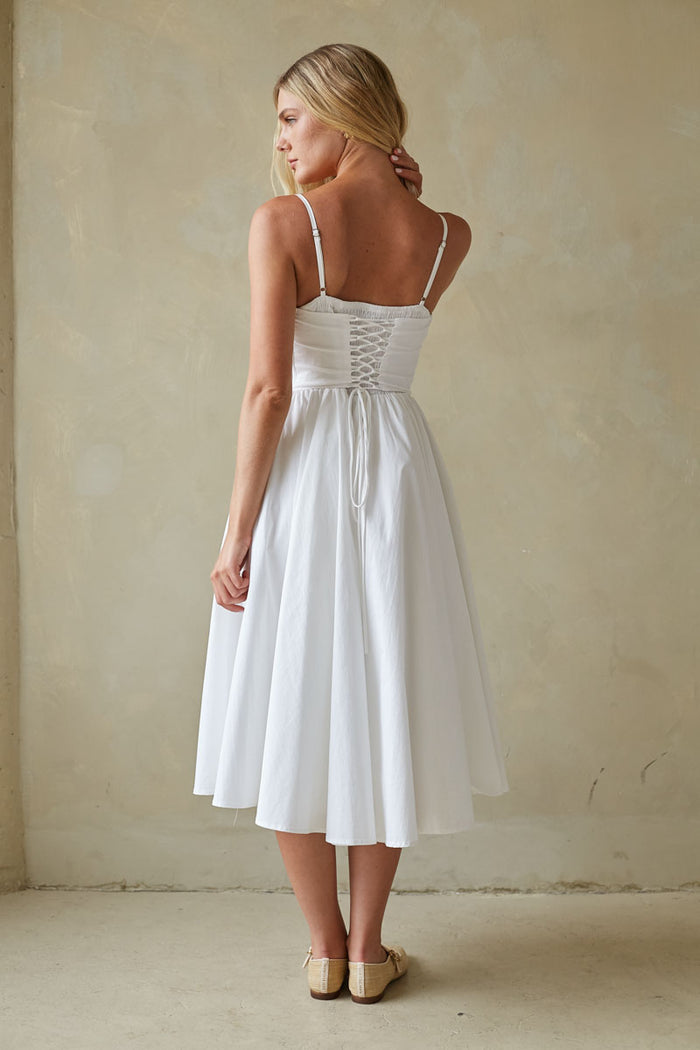 Woman wearing a white dress against a beige wall