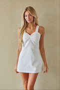 Woman wearing a white dress against a beige background