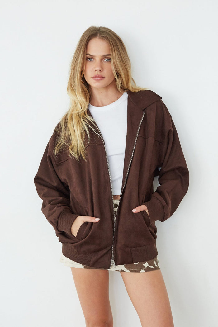Woman wearing a brown zip-up hoodie against a white background