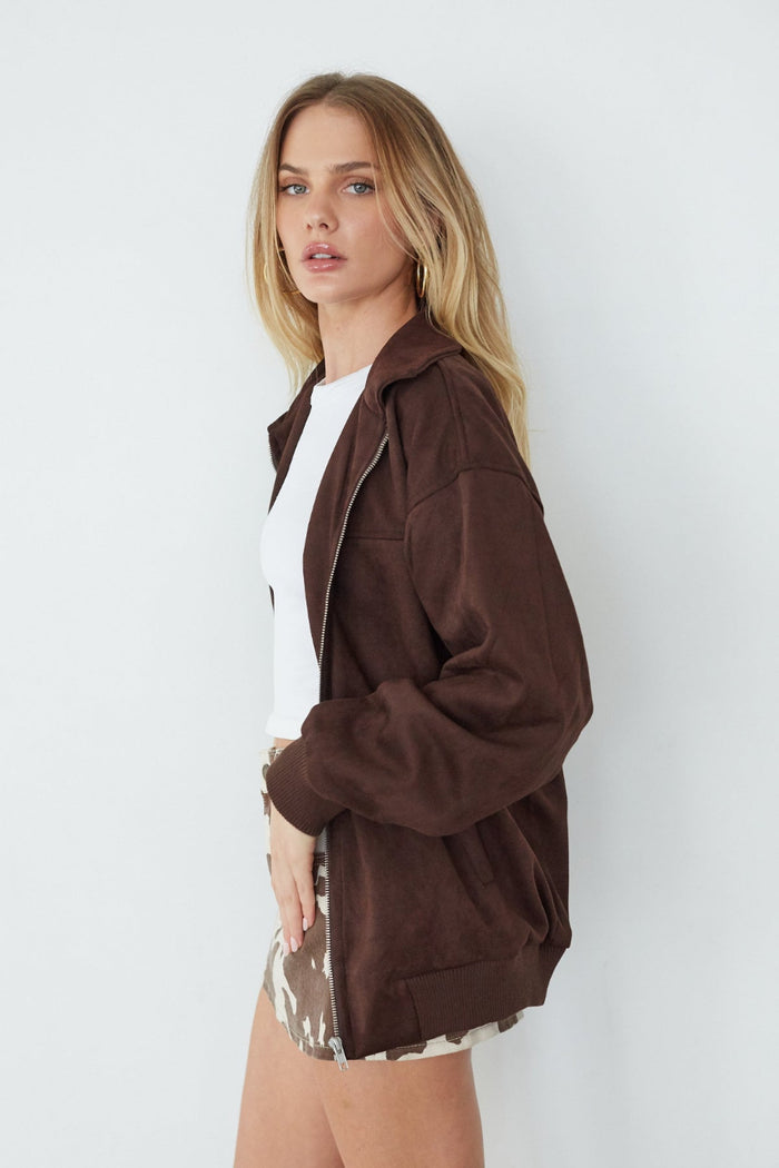 Woman wearing a brown jacket over a white shirt on a white background