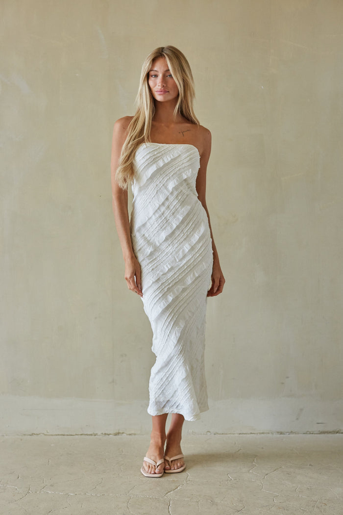 Woman wearing a white strapless dress against a plain background