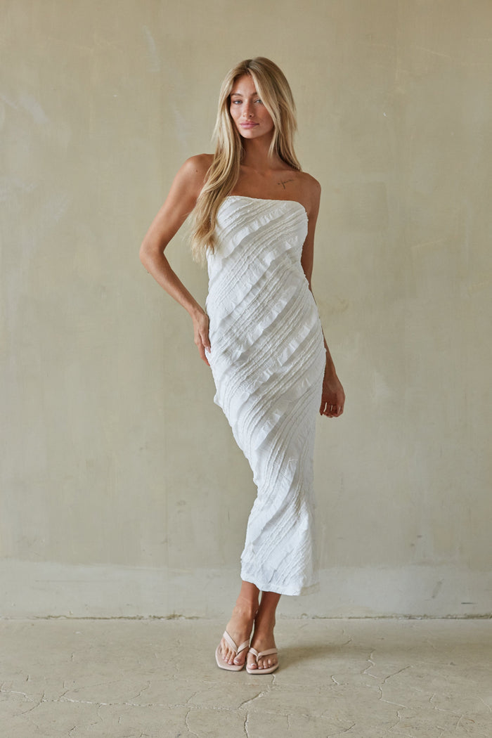 Woman wearing a white strapless dress against a plain background