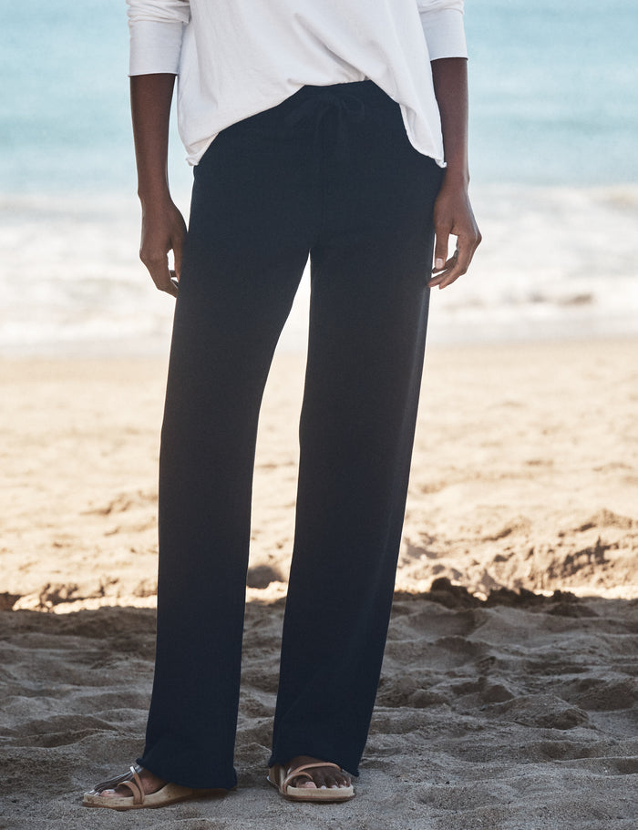 Person wearing navy pants and a white shirt on a beach