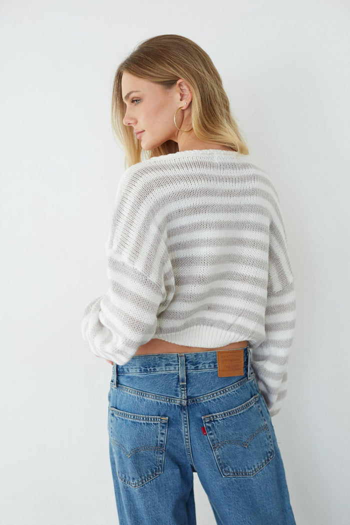 Woman wearing a striped sweater and blue jeans against a white background
