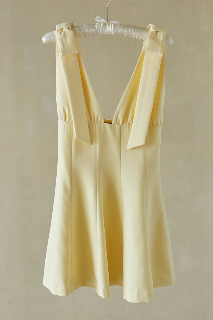 yellow-image | Yellow dress hanging on a hanger against a plain background