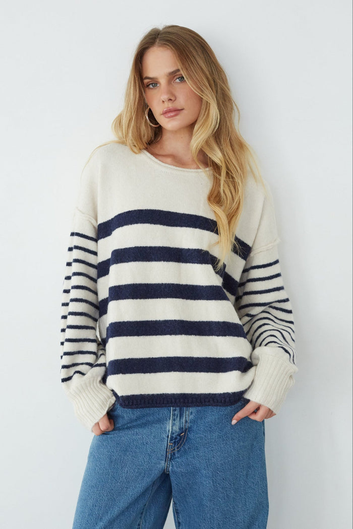 Woman wearing a striped sweater and jeans against a white background