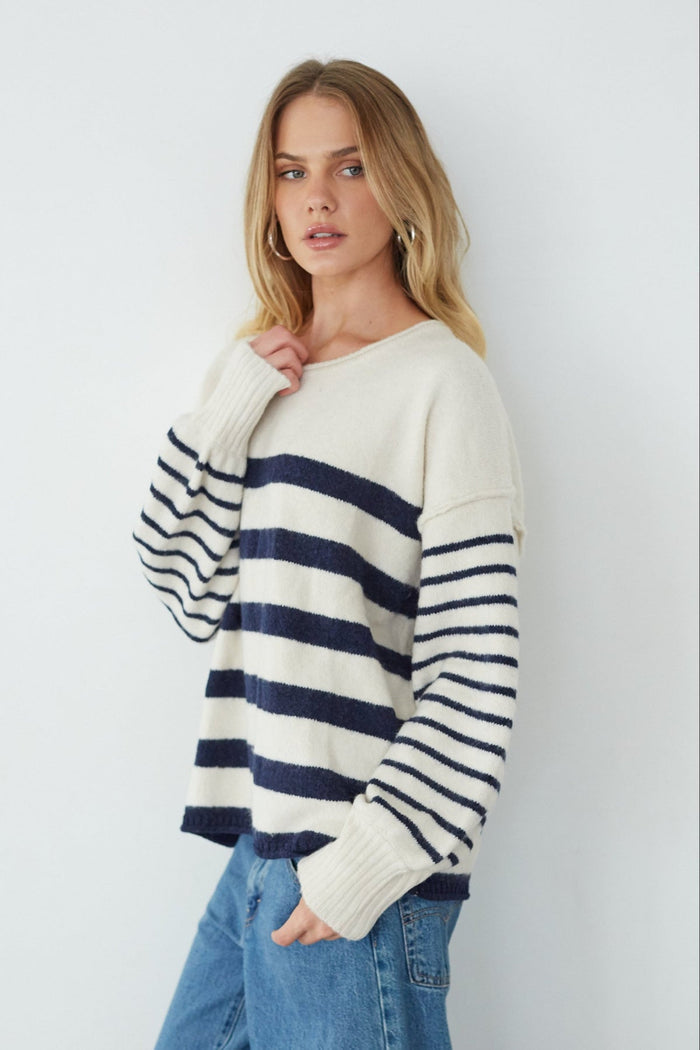 Woman wearing a striped sweater and jeans against a plain background