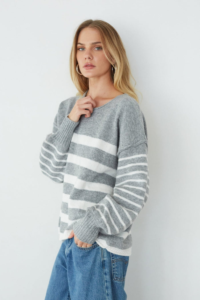 Woman wearing a gray and white striped sweater against a white background