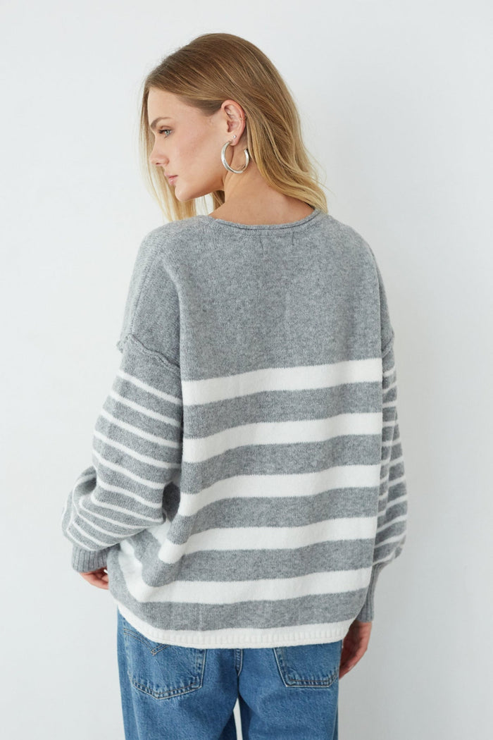 Woman wearing a gray and white striped sweater against a white background