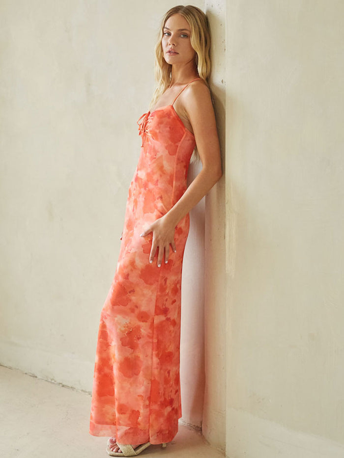 Woman wearing a coral floral dress against a white wall