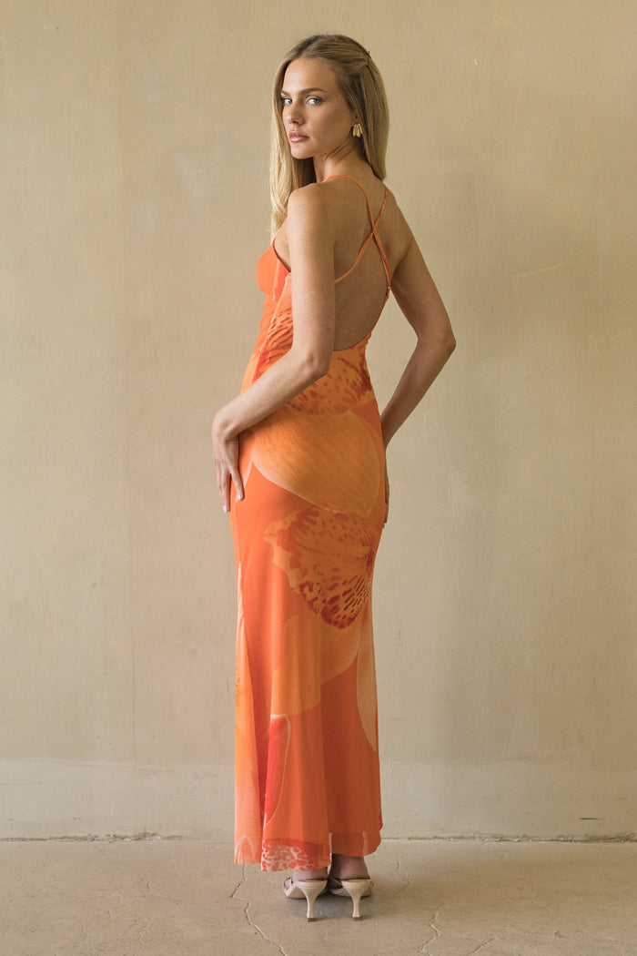 Woman wearing an orange dress against a beige wall