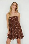 brown-image | Woman wearing a brown polka dot dress against a white background