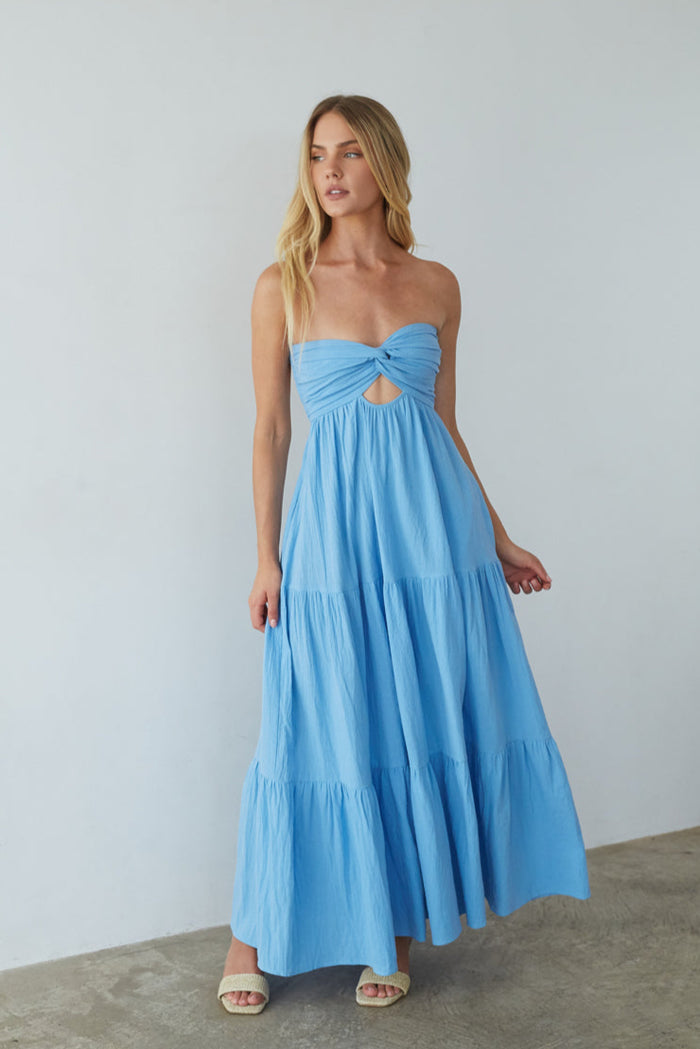 blue-image | Woman wearing a blue strapless dress with a tiered skirt against a plain background