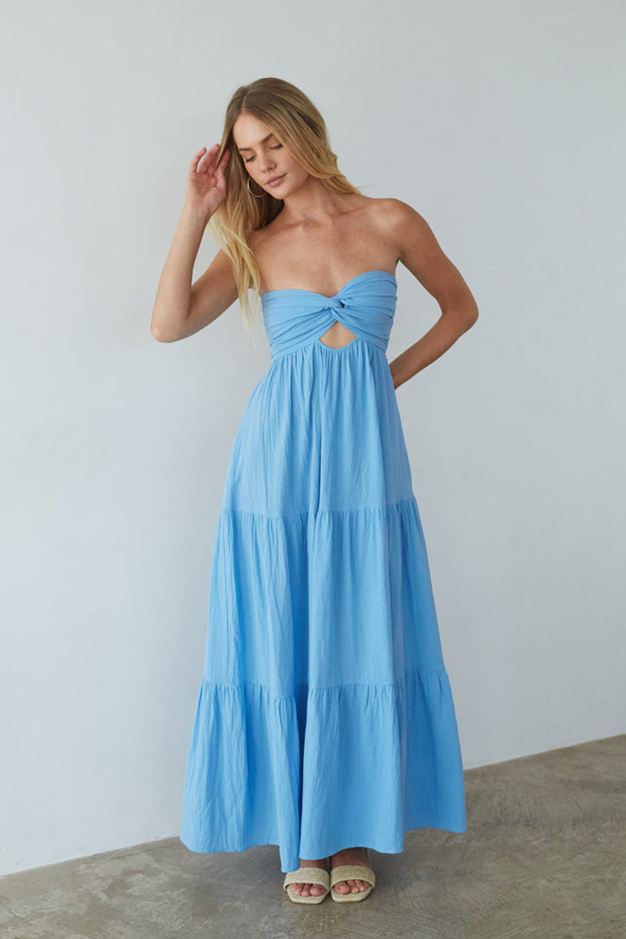 Woman wearing a blue strapless dress with cutout details on a plain background