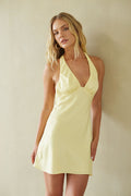 yellow-image | Woman wearing a light yellow halter neck dress against a plain background