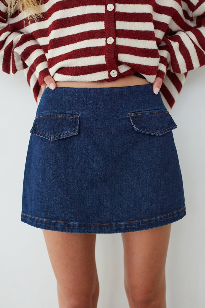 Person wearing a red and white striped sweater and blue denim skirt on a white background