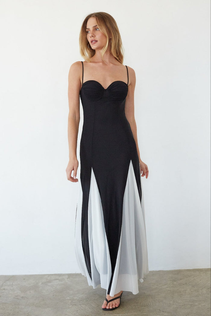 Woman wearing a black and white evening gown against a plain background