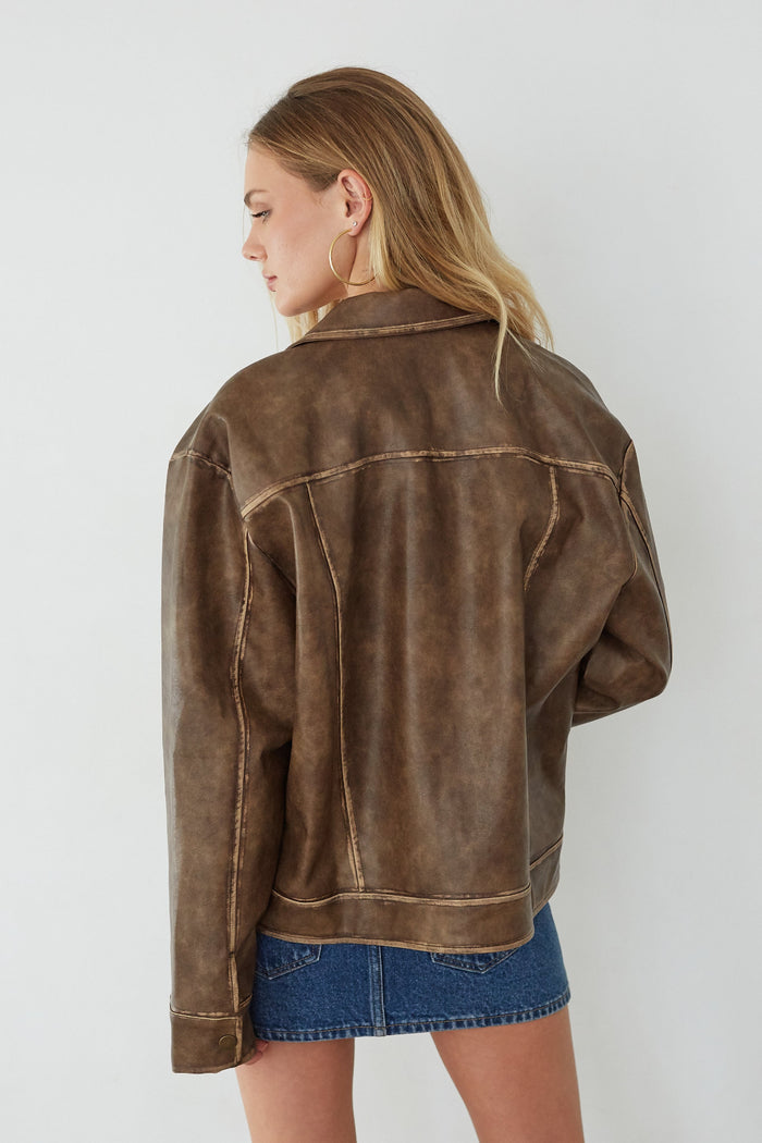 Woman wearing a brown leather jacket and denim skirt on a white background