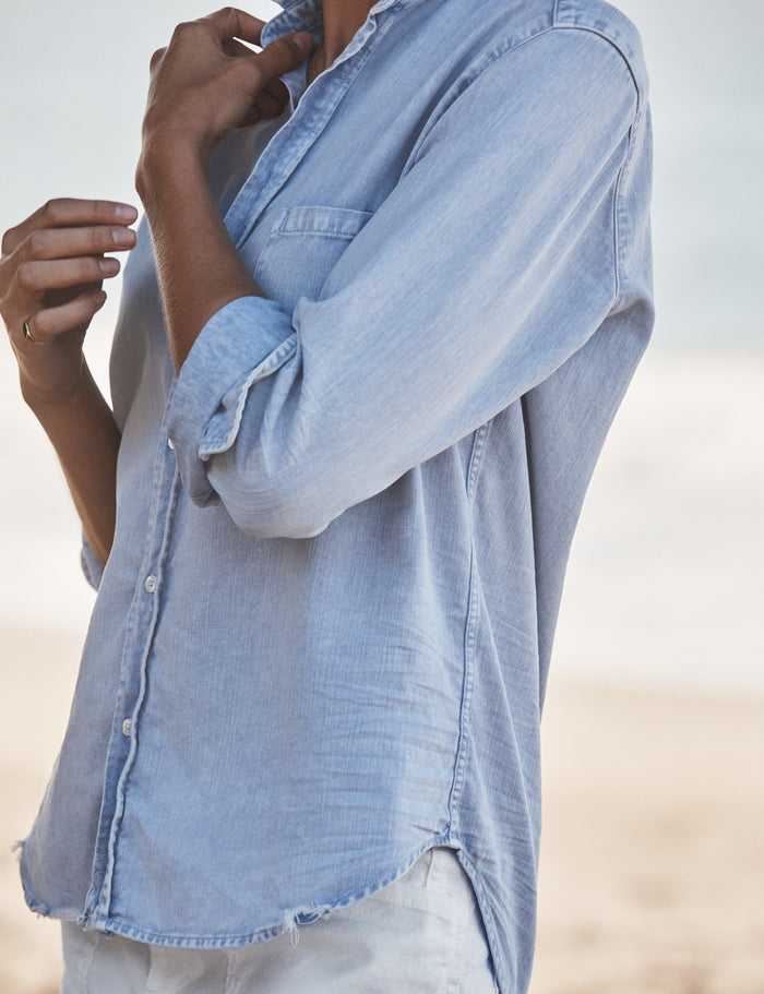 Light blue denim shirt with rolled-up sleeves on a blurred background