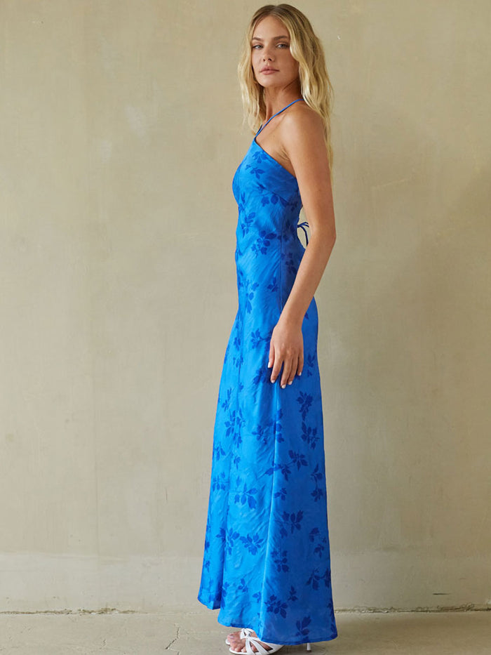 Woman wearing a blue floral dress against a beige background