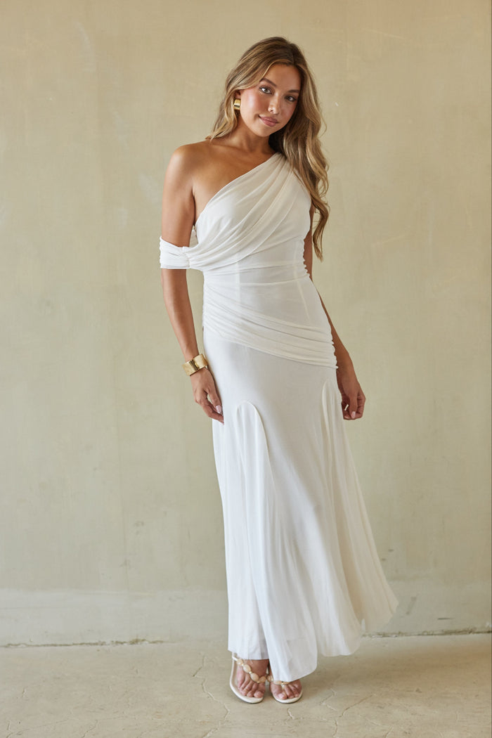 Woman wearing a white one-shoulder dress against a plain background