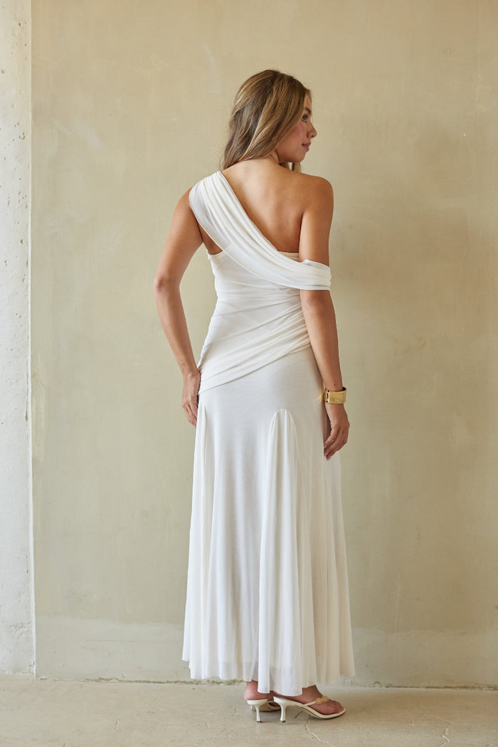 Woman wearing a white one-shoulder dress against a plain background
