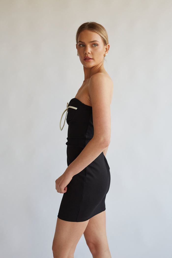 side view of black strapless mini dress with white bow detailing