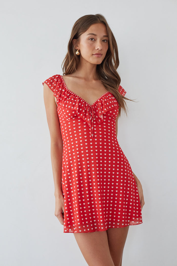 red-image | front-image | flirty red mini dress | sweetheart neckline dress | ruffle sleeve summer dress | vibrant red mini dress with white heart prints, a ruffled neckline, and flutter sleeves for a romantic touch