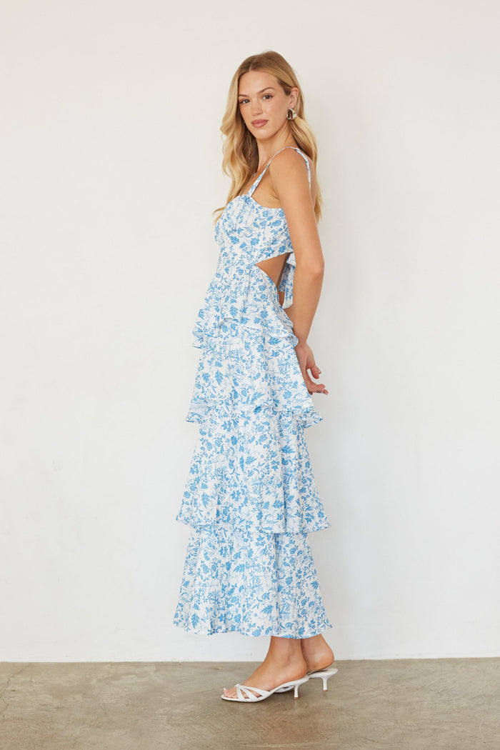 Woman wearing a blue floral dress with cut-out details on a white background